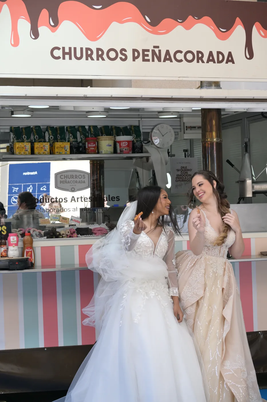 Dos novias con un churro en la mano delante del food truck de Churros Peñacorada